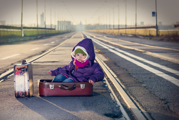 Mała dziewczynka siedzi w walizce w pobliżu linii kolejowej - Zdjęcie, obraz