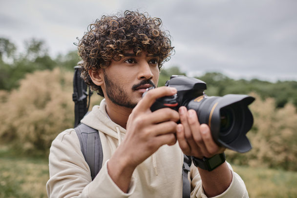 συμπυκνωμένη ινδική φωτογράφος χρησιμοποιώντας επαγγελματική φωτογραφική μηχανή και τη λήψη φωτογραφιών σε φυσική τοποθεσία - Φωτογραφία, εικόνα