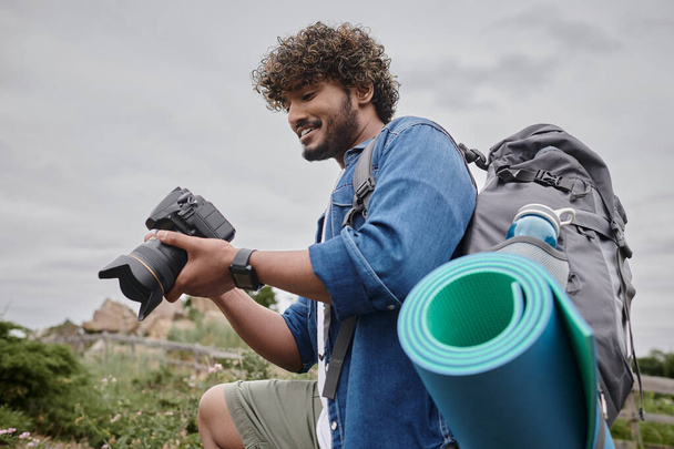 koncepcja fotografii podróżniczej, szczęśliwy indiański Backpacker trzyma aparat cyfrowy podczas podróży - Zdjęcie, obraz