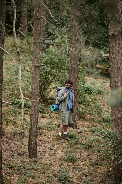 onnellinen intialainen reppumatkailija kiharat hiukset kävely metsässä, luonnollinen sijainti, retkeilijä reppu - Valokuva, kuva