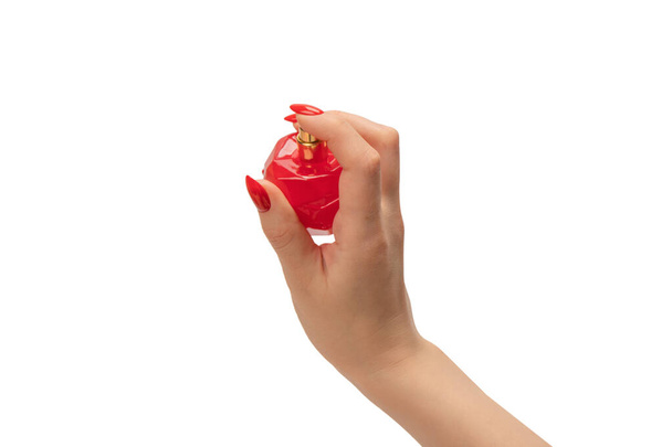 Flacon rouge de parfum à la main femme avec des ongles rouges isolés sur un fond blanc. Application de parfum. - Photo, image