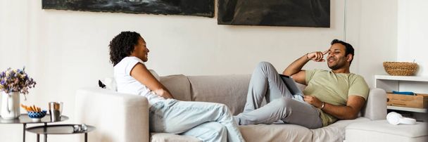 Middle eastern man and woman smiling and talking while resting on couch at home - Foto, immagini