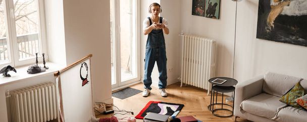 Young white man taking photo on cellphone while working on craft rug at home - Valokuva, kuva