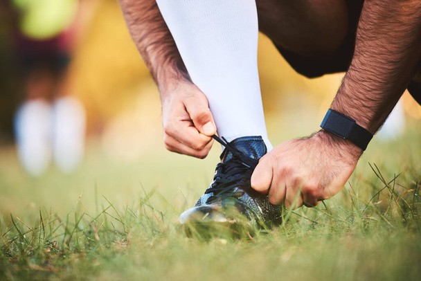 Handen, rugby atleet en stropdas schoenen om te beginnen met trainen, sporten of fitness. Sport, speler en man gelijkmakende laarzen bij trainingsvoorbereiding, wedstrijd of wedstrijd voor gezond lichaam of welzijn op het veld buiten. - Foto, afbeelding