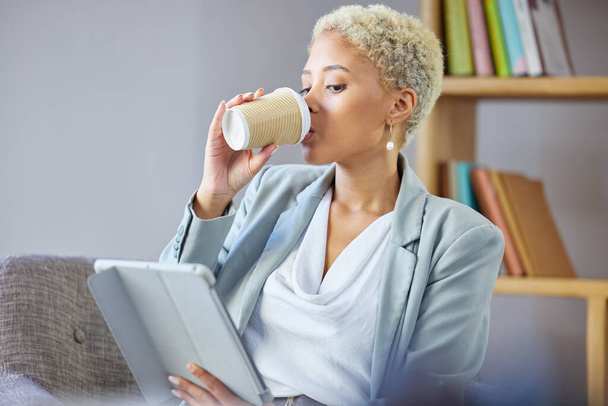 Coffee break, tablet and business woman on a sofa relax, reading and checking email while working remote. Freelance, tea and female in living room with social media, search and ebook in her home. - Photo, Image