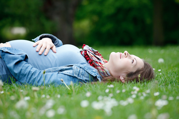 Beautiful pregnant woman relaxing on grass - Photo, Image
