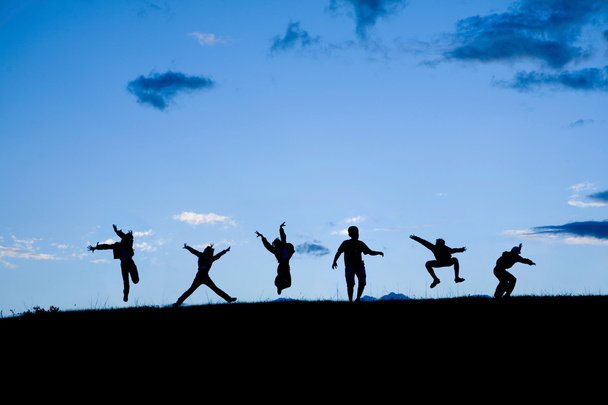 Siluetas de seis niños saltando juntos en el cielo azul
 - Foto, Imagen