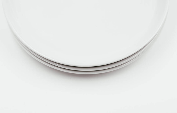 Λευκό στρογγυλό πιάτο σε λευκό φόντο αντίγραφο χώρου. Υψηλής ποιότητας φωτογραφία - Φωτογραφία, εικόνα