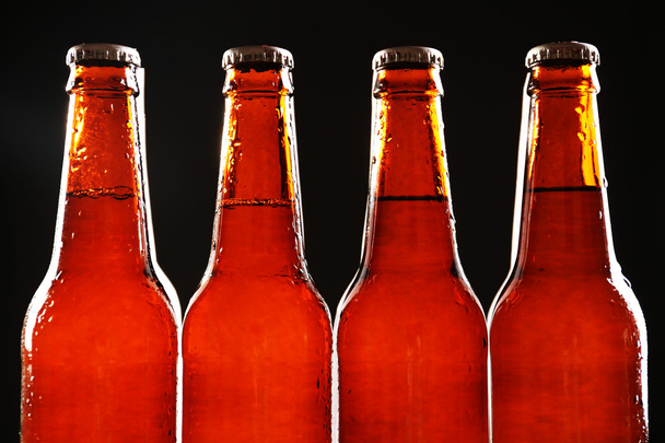 Glazen flesje bier op donkere achtergrond - Foto, afbeelding