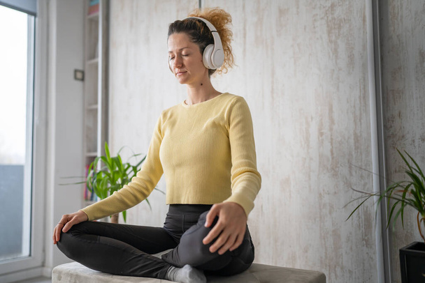 jedna žena dospělý kavkazský ženský tisíciletý pomocí sluchátek pro on-line řízené meditace cvičení bdělosti jóga s očima zavřenýma na podlaze doma skuteční lidé kopírovat prostor self-care koncept - Fotografie, Obrázek