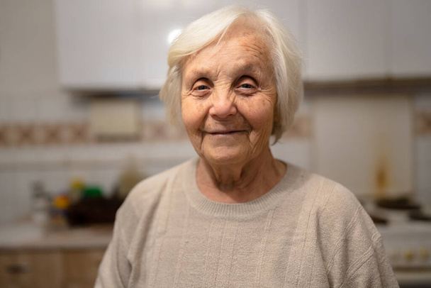 one woman senior old female caucasian pensioner standing at home waist up portrait looking to the camera dementia alzheimer's disease concept positive emotion copy space - Photo, Image