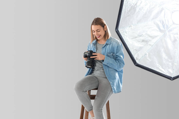 Γυναίκα φωτογράφος με επαγγελματική κάμερα κάθεται στο στούντιο - Φωτογραφία, εικόνα