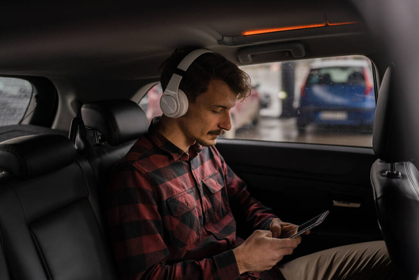 один чоловік дорослий білий чоловік сидить в машині з навушниками на голові слухати музику або подкаст, приймаючи гальма під час подорожі чекаючи і розслабляючись реальні люди копіюють простір сучасного способу життя
 - Фото, зображення