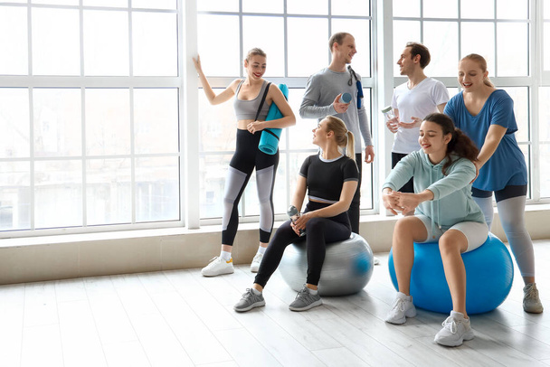 Group of sporty young people with bottles of water and equipment in gym - Foto, Bild