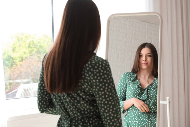 Молода жінка дивиться в дзеркало вдома
 - Фото, зображення