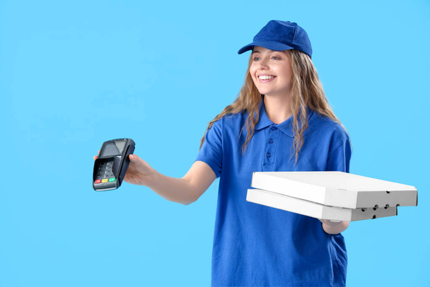 Corriere donna con cassette della pizza e terminale di pagamento su sfondo blu - Foto, immagini