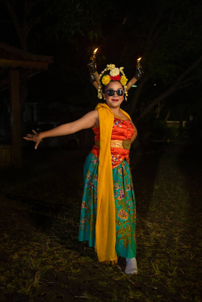 egy hagyományos jávai táncos áll és táncol rugalmas testtel, miközben napszemüveget visel éjszaka - Fotó, kép