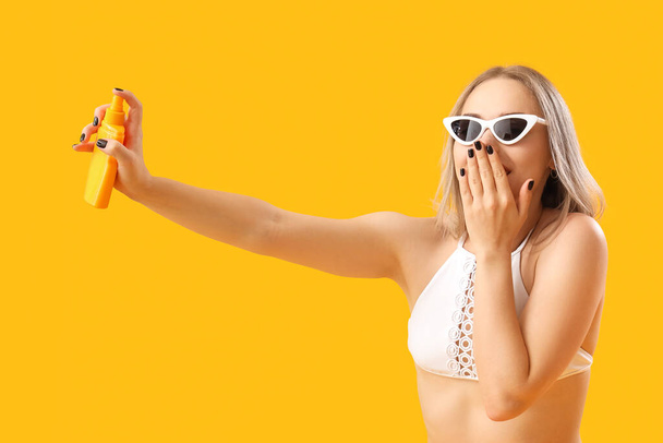 Молода жінка з сонцезахисним кремом на жовтому фоні
 - Фото, зображення