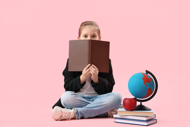 Little schoolgirl with books, globe and apple on pink background - Photo, Image