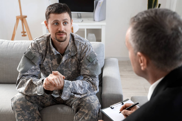 Dojrzały psycholog pracujący z żołnierzem w biurze - Zdjęcie, obraz