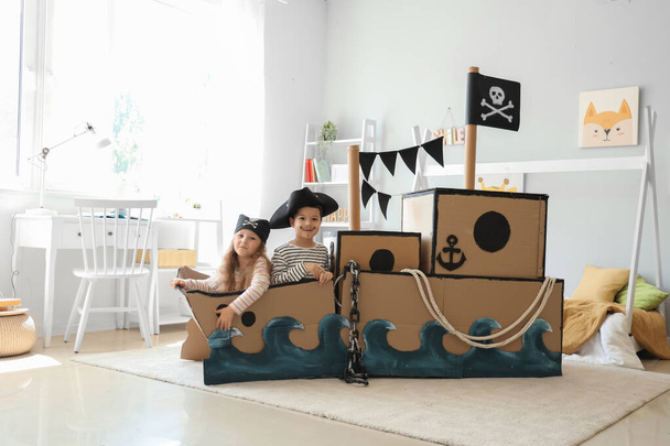 Χαριτωμένοι μικροί πειρατές παίζουν σε χαρτονένιο πλοίο στο σπίτι - Φωτογραφία, εικόνα