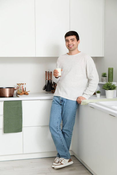 Young man with glass of milk in kitchen - Zdjęcie, obraz