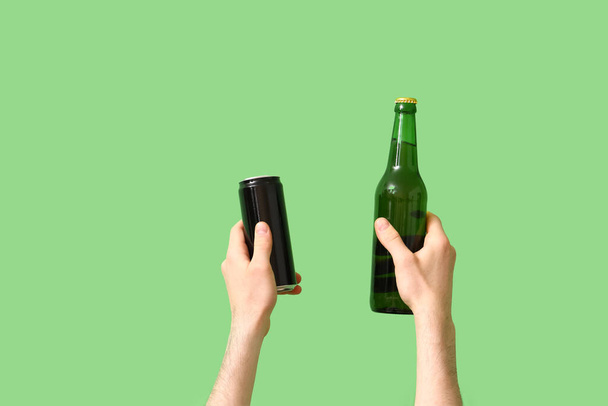 Mies, jolla on pullo ja tölkki olutta vihreällä taustalla - Valokuva, kuva