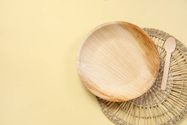 Weidenmatte mit Holzteller und Löffel auf beigem Hintergrund - Foto, Bild