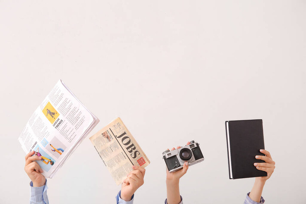 Manos femeninas con periódicos, cámara fotográfica y cuaderno sobre fondo claro - Foto, imagen