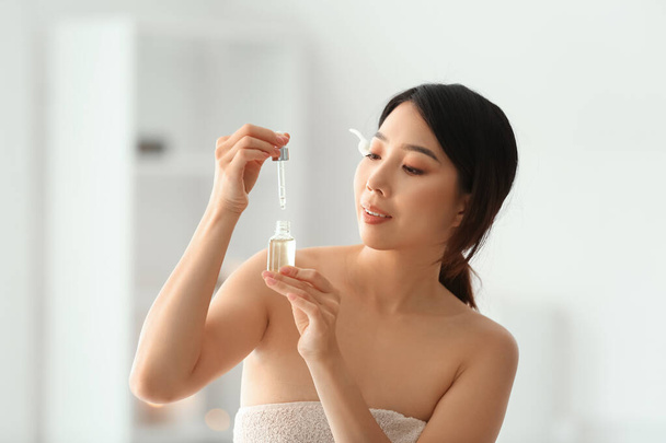 Mujer asiática bastante joven con aceite esencial en el salón de spa - Foto, imagen