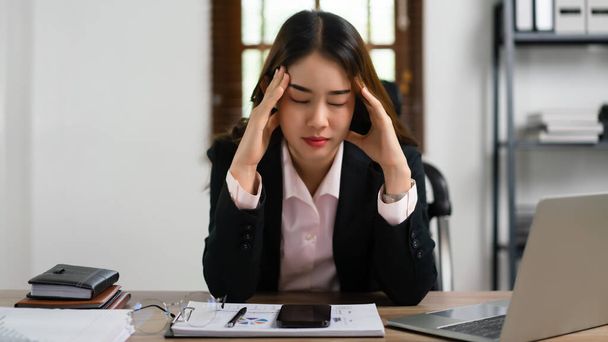 Mujer de negocios masajeando su cabeza para relajarse mientras que el dolor de cabeza y agotado después de exceso de trabajo. - Foto, Imagen