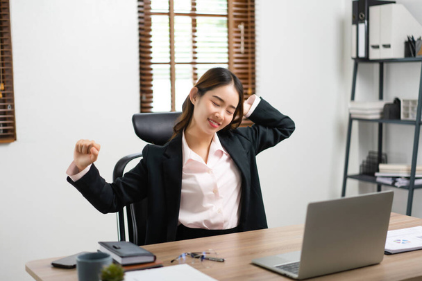 Femme d'affaires lever les bras à étirer pour la détente après avoir épuisé de surmenage sur le lieu de travail. - Photo, image