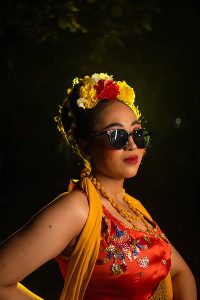 ένας παραδοσιακός χορευτής της Ιάβας στέκεται και χορεύει με εύκαμπτο σώμα φορώντας γυαλιά ηλίου τη νύχτα - Φωτογραφία, εικόνα