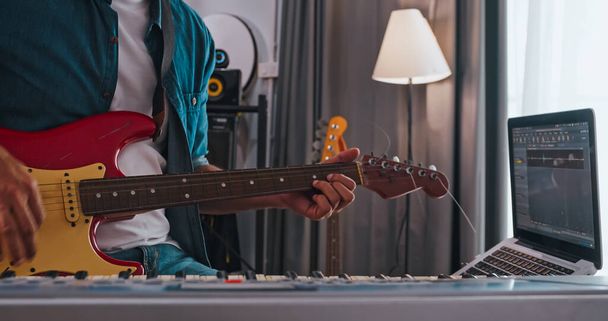 Evdeki dijital stüdyoda elektro gitar çalan bir müzisyen. Bir besteci bir melodi yaratmak için modern ekipman kullanıyor.. - Fotoğraf, Görsel