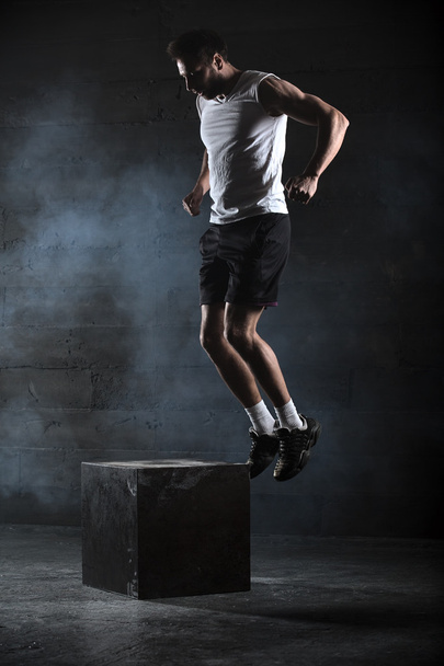 Athlete gave exercise. Jumping on the box. Phase touchdown. Stud - Фото, изображение