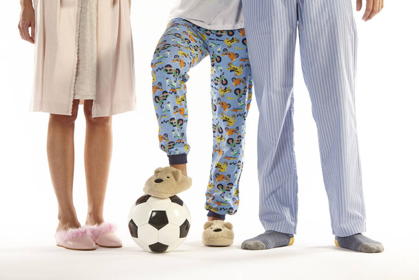 Perhe pyjamassa jalkapallolla. Jalat yksityiskohtaisesti. Yövaatteet - Valokuva, kuva