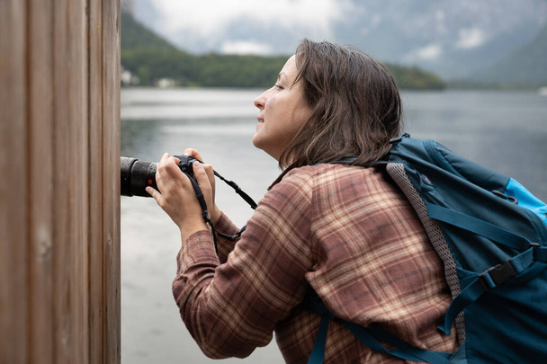 Joven fotógrafa fotografiando en un lago detrás de una pared de madera, concepto creativo, Hallstatt, Austria. Foto de alta calidad - Foto, Imagen