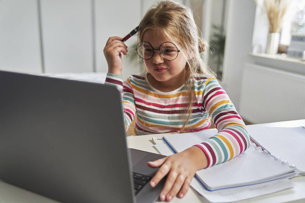 Caucásico elemental chica de edad estudiando en el ordenador portátil y tener problemas con la comprensión - Foto, imagen