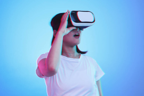 Mujer, VR y visión con wow para la experiencia futurista, juegos 3D y educación general z o aprendizaje digital e. Estudiante con sorpresa para realidad virtual, alta tecnología y gafas en fondo de estudio azul. - Foto, imagen