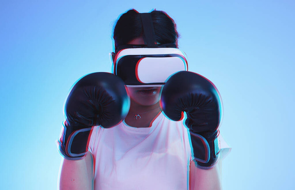AI, metaverso y una boxeadora jugando en un fondo azul en el estudio para la aptitud o el ejercicio. Realidad virtual, deportes y entrenamiento con una joven jugadora boxeando un juego de fantasía en línea para la salud. - Foto, imagen