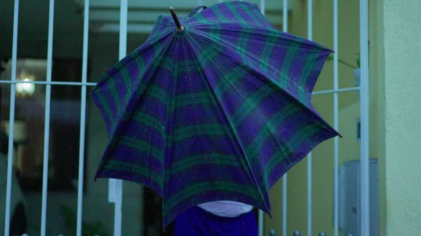 Hombre mayor abre puerta, sale de casa con paraguas bajo la lluvia, camina por la acera urbana - Foto, Imagen