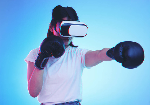 AI, metaverse és egy gamer nő boksz a kék háttérben stúdió fitness vagy a testmozgás. Virtuális valóság, sport és képzés egy fiatal női bokszoló játszik egy online fantasy játék az egészség. - Fotó, kép