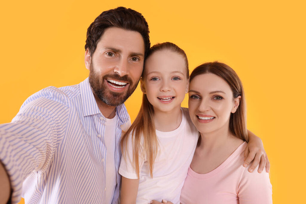 Happy family taking selfie on orange background - Foto, Imagem