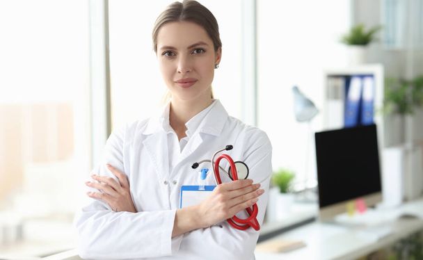 Portret van een lachende vrouwelijke arts in een witte jas in een medisch kantoor. Medina-dienstenconcept - Foto, afbeelding
