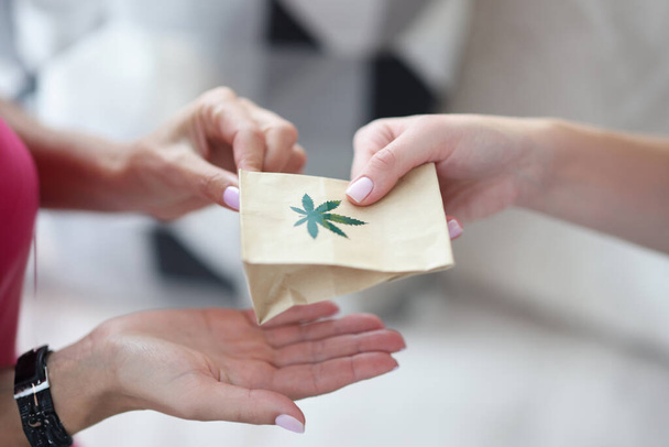Handing over paper bag with marijuana sign. Marijuana delivery service concept - Photo, Image