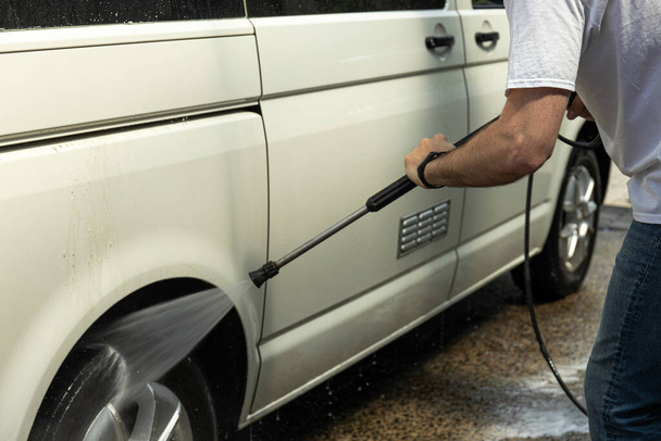 Mężczyzna myje samochód w samoobsługowej myjni samochodowej - Zdjęcie, obraz