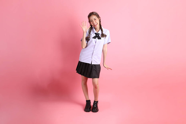 La ragazza asiatica in uniforme studentesca tailandese in piedi sullo sfondo rosa. - Foto, immagini