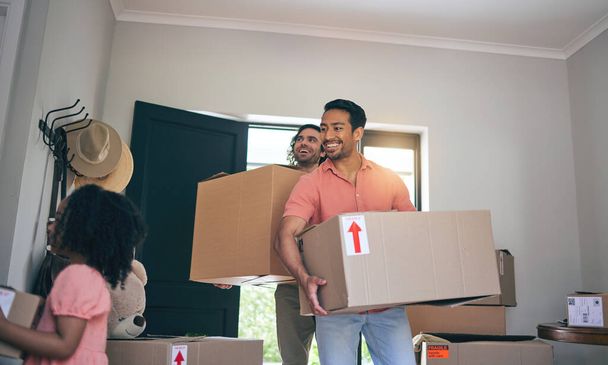 Happy, new home and box moving with child and gay parents with cardboard package and family. Smile, kid and lgbt people together with real estate and property mortgage in a house helping father. - Photo, Image