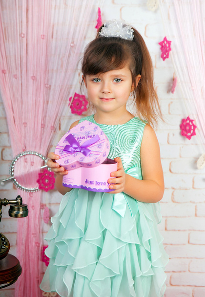 yeşil giysili bir hediye de sahne tutan bir küçük şirin kız - Fotoğraf, Görsel