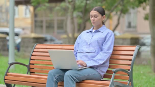 femme hispanique en utilisant un ordinateur portable avec douleur au dos tout en étant assis à l'extérieur - Séquence, vidéo